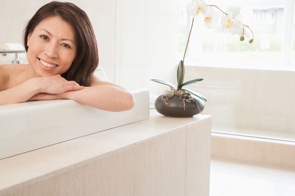 Asian woman on sofa beside orchid