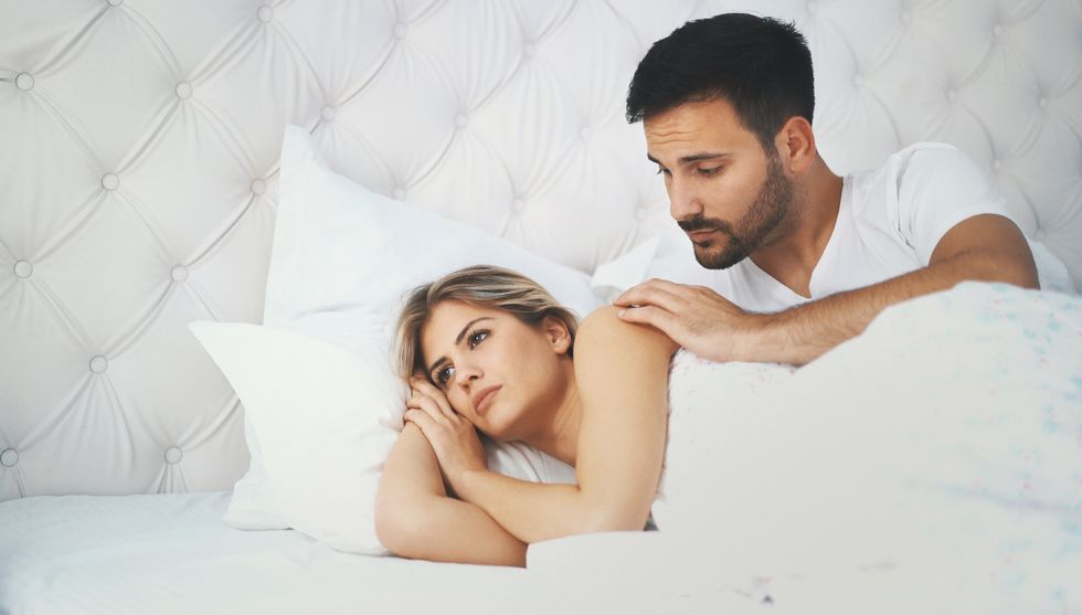couple laying in bed, woman is sad because her vagina is burning during sex
