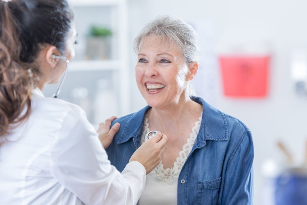 doctor checking heart of woman patient