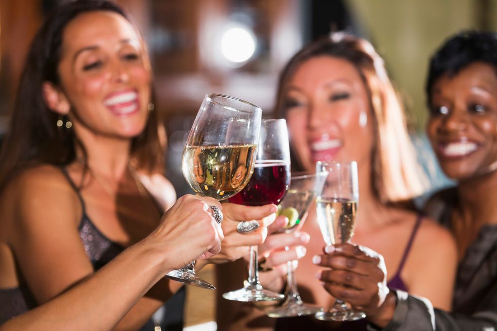 group of four multi-ethnic women having fun together at a restaurant bar, drinking