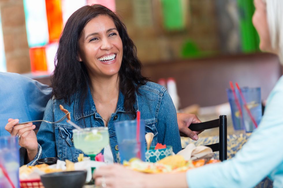 Hispanic woman smiling during restaurant dinner with friends 