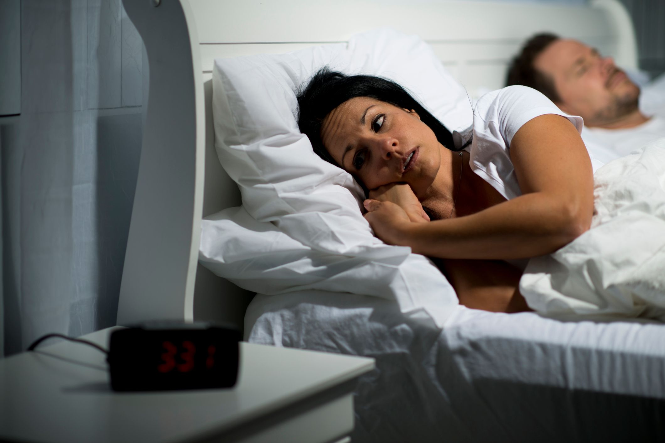 woman lying in bed staring at the clock