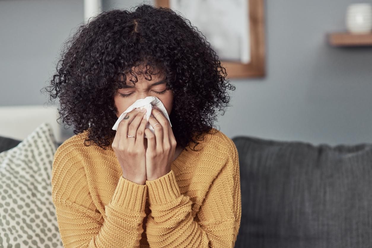 young woman blowing her nose with a tissue at home