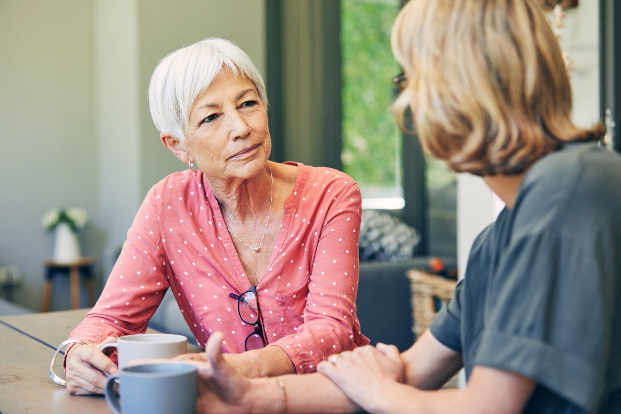 woman and her elderly mother having coffee and a chat at home