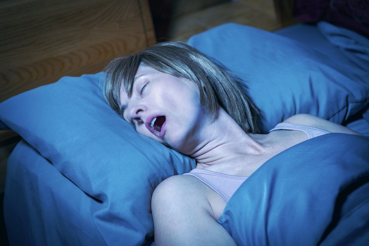 woman in bed at night with her mouth open snoring obnoxiously