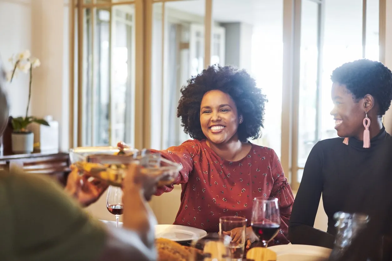 Happy friends sitting together at dining table