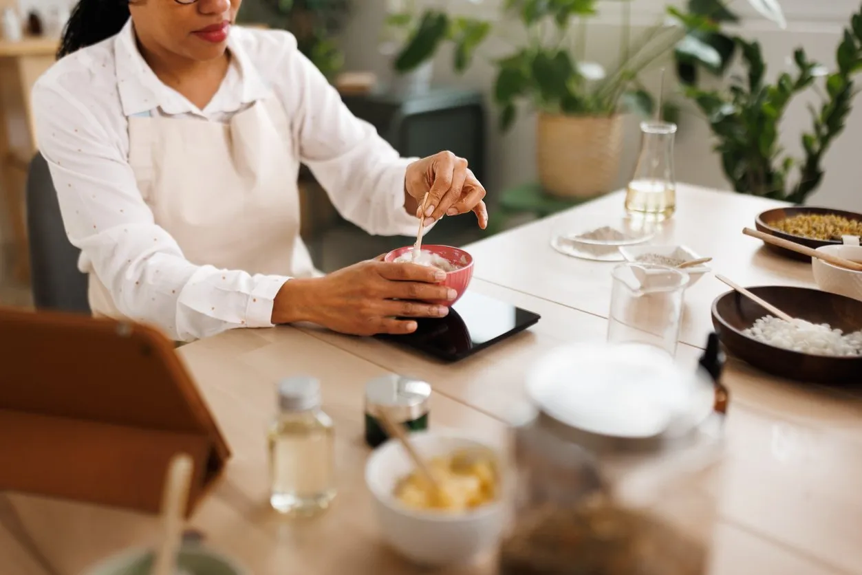 Woman mixing ingredients for homemade hand cream at her workshop