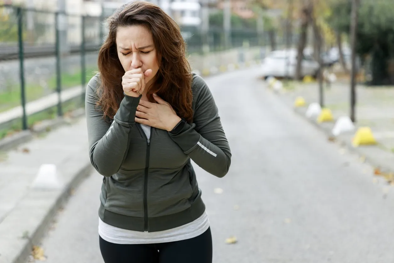 woman coughing while walking