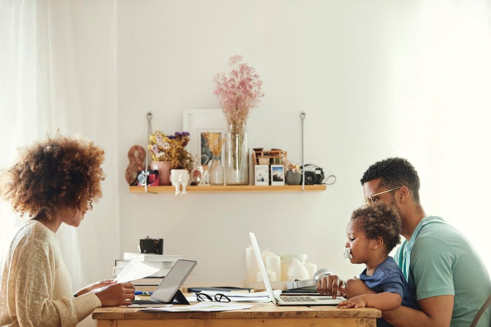 Mother using digital tablet for working from home. Father using laptop with son at table