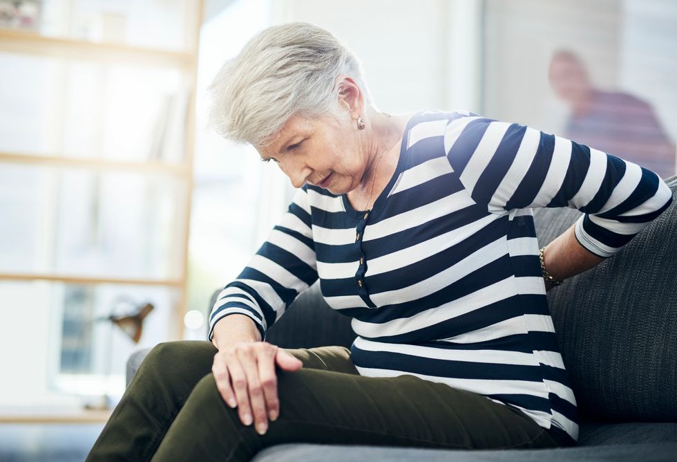 senior woman experiencing back pain at home