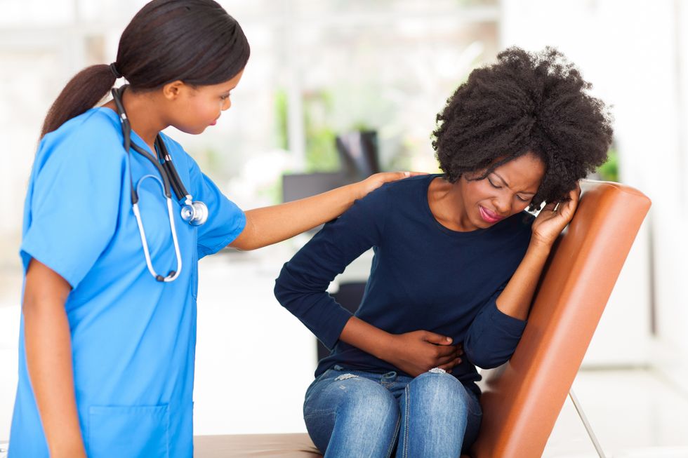urse comforting female patient suffering from fibroids, in doctor's office