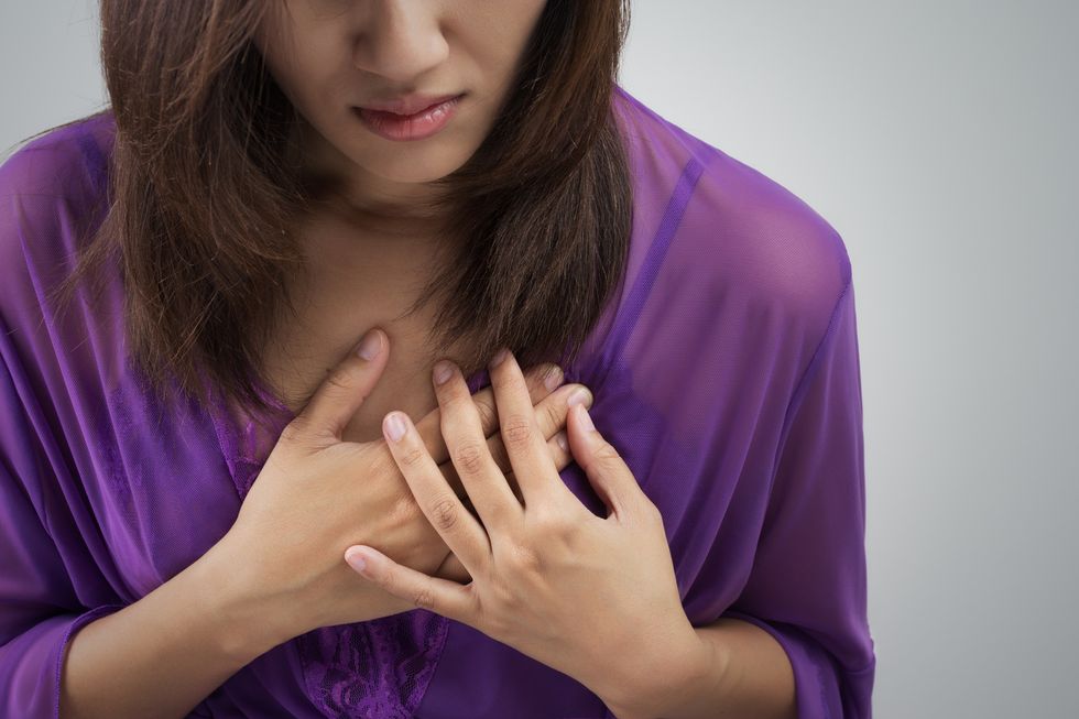 Woman holding chest to indicate heart attack