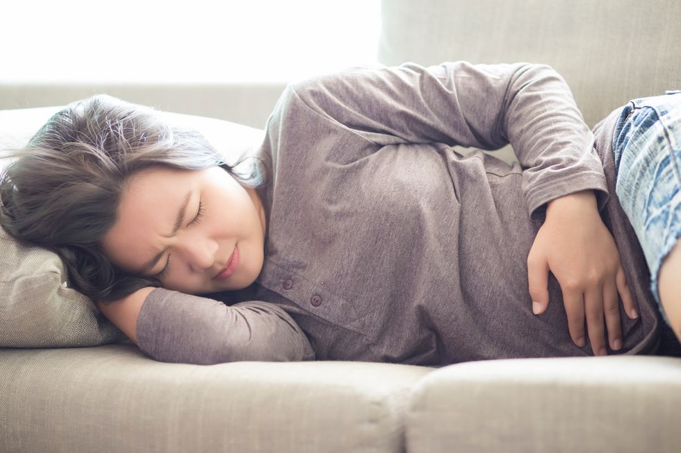 woman laying on the couch suffering from a leaky gut