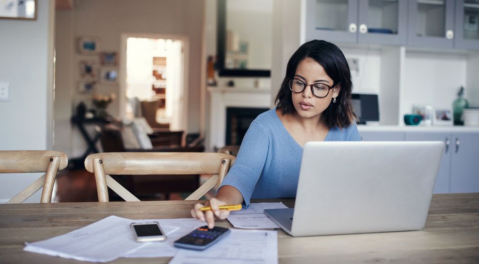 woman using a laptop and calculator while working from home